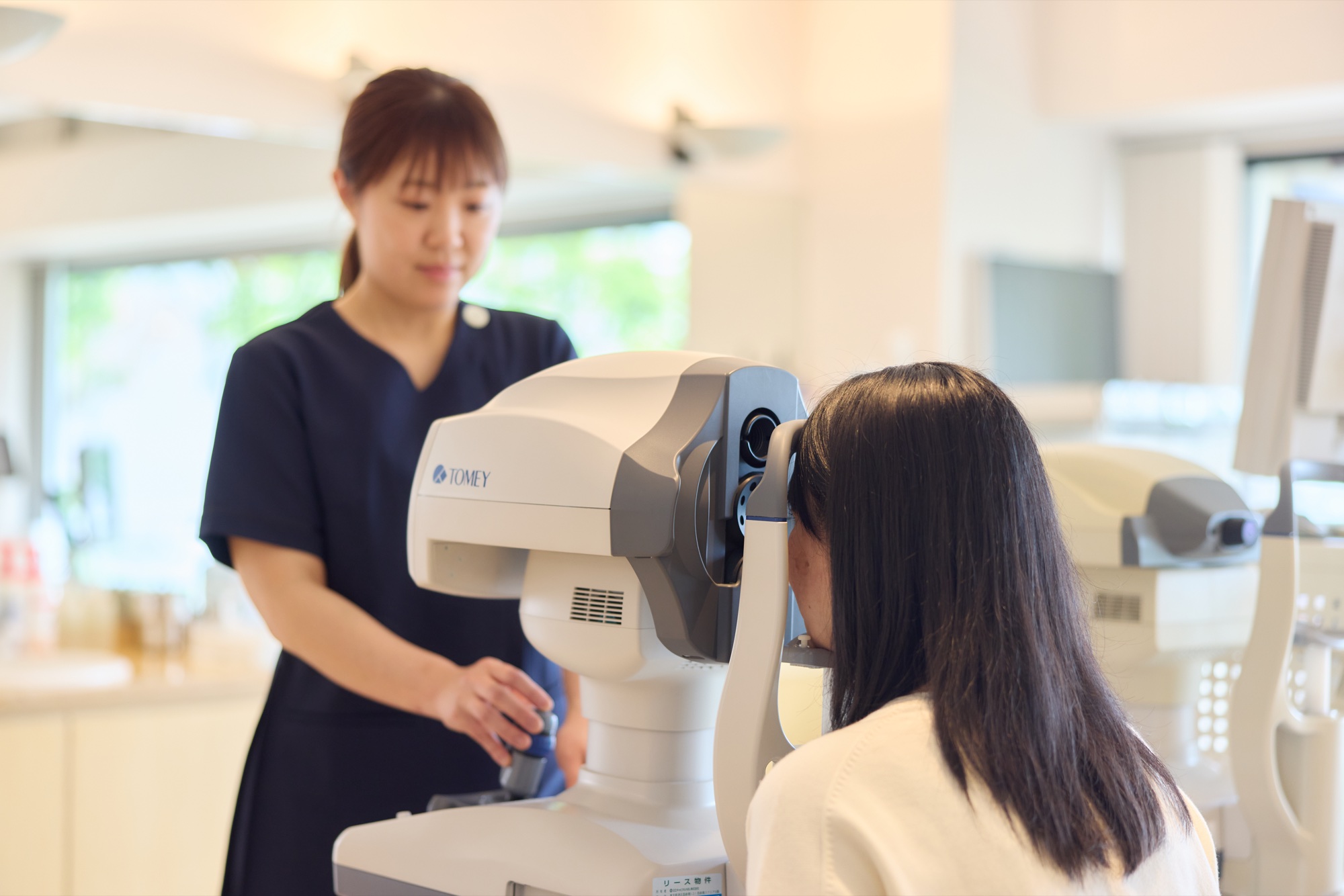スタッフが検査機器を操作し、患者さまの目を調べている様子