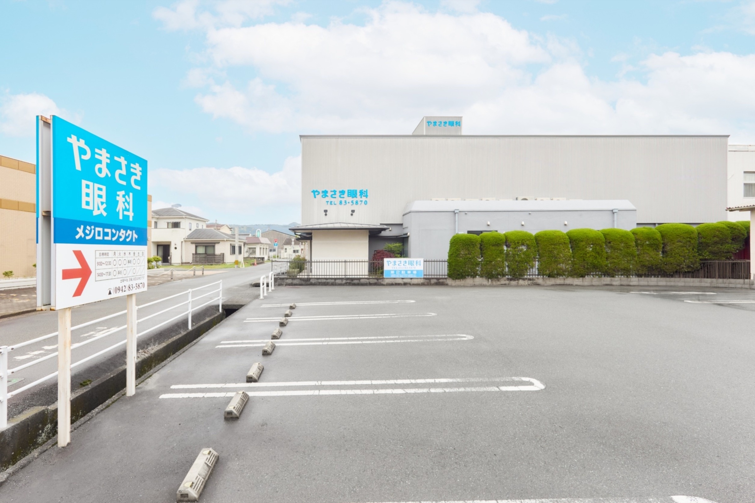 駐車場と案内看板が見える、やまさき眼科の外観