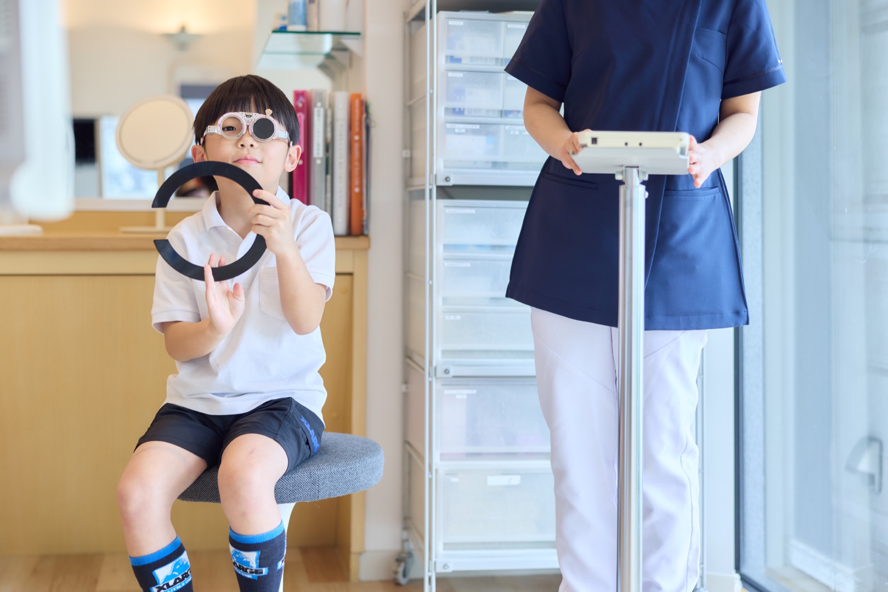 スタッフと一緒に見え方の検査を受けるお子さま